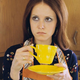 Woman staring off into distance while drinking out of yellow coffee mug